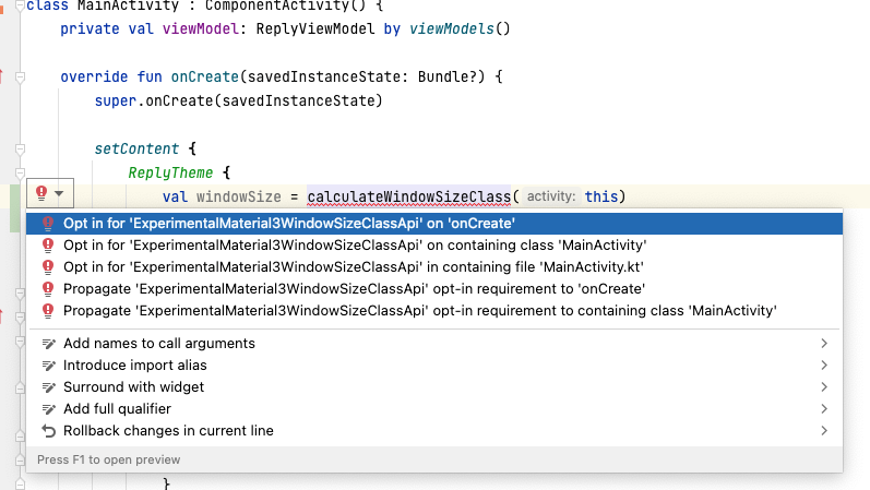 En el código, se selecciona la línea "val windowSize = calculateWindowSizeClass(this)" y se muestra el ícono de bombilla a la izquierda de la línea de código. Debajo de la bombilla seleccionada, hay una lista de opciones para abordar el error, con la opción "Opt in for 'ExperimentalMaterial3WindowSizeClassApi' on 'onCreate'" seleccionada.